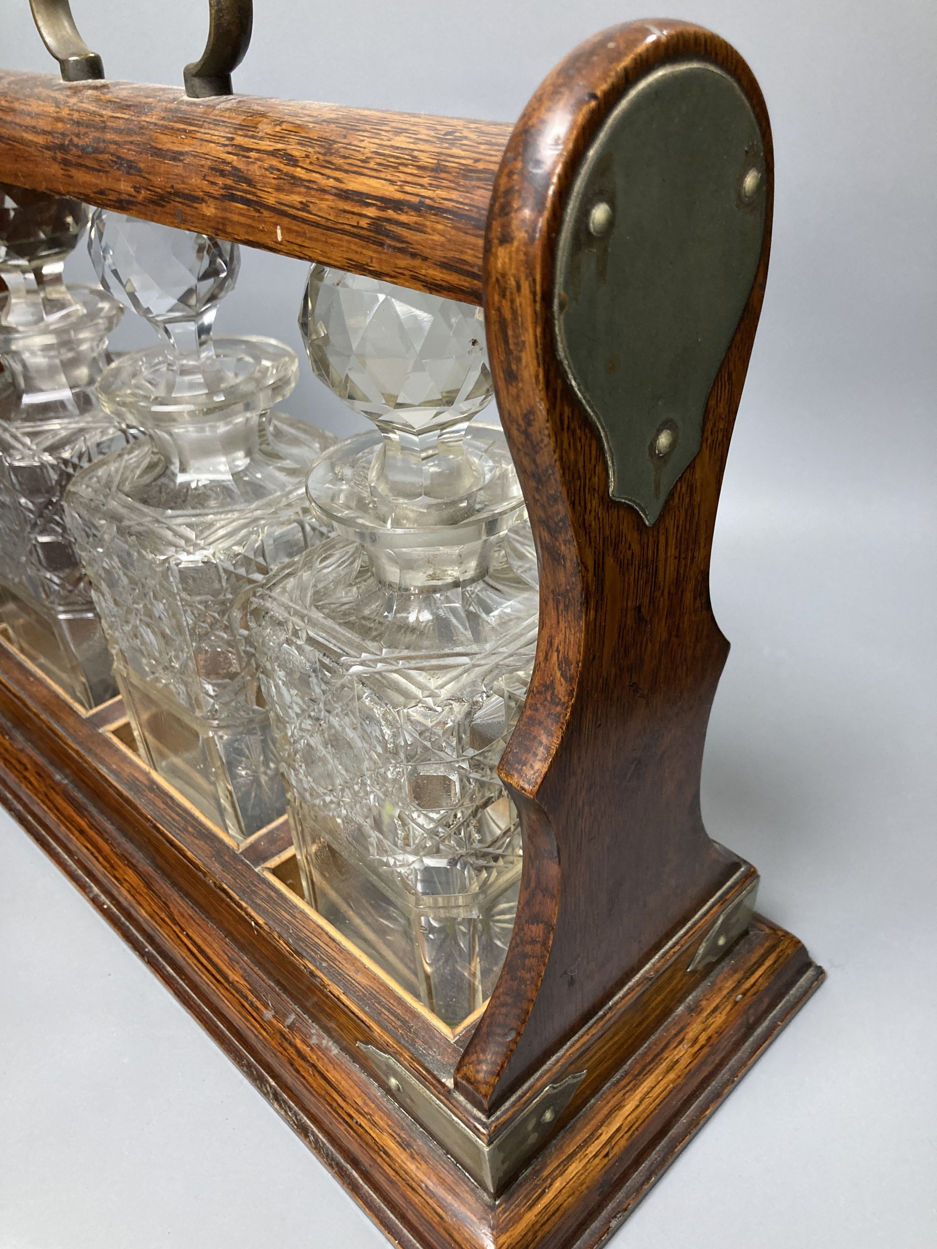 An Edwardian oak three decanter tantalus